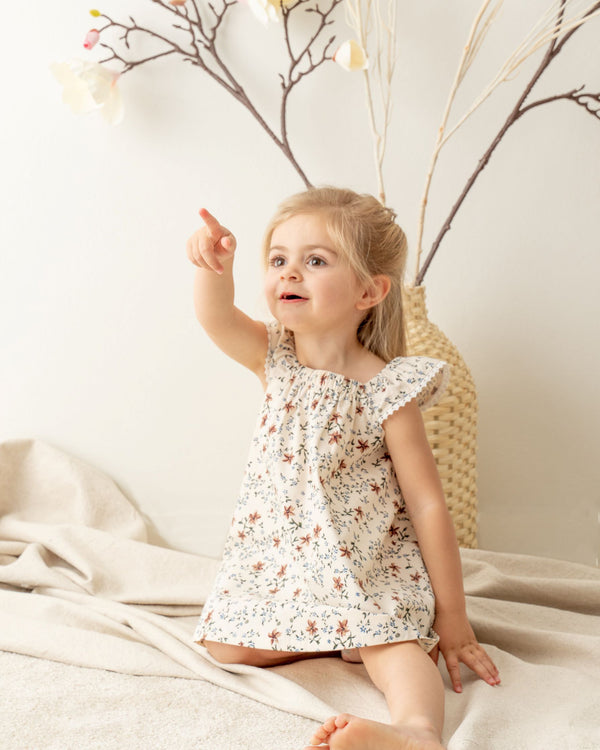 Little girl wearing Organicline Floral A-Line dress. Featuring angle-sleeves with baby lace eyelet on the edge and a gentle elastic square neckline, our softly made floral print pattern dress offers a classic look in vintage style. 