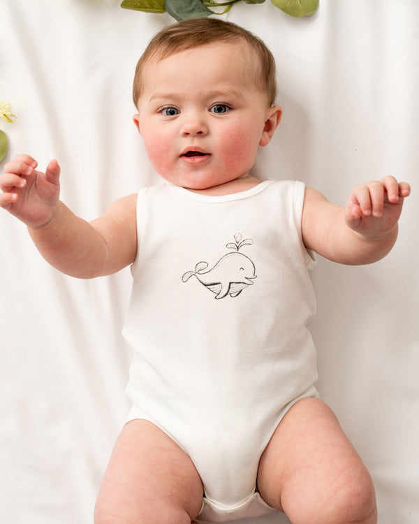 Sleeveless baby bodysuit made of super soft interlock organic cotton certified by GOTS . Featuring a hand draw little baby dolphin embroidered at the front. Snap buttons at the bottom for easy dressing and nappy changing.  Natural white color ideal for babies with the most sensitive skin.